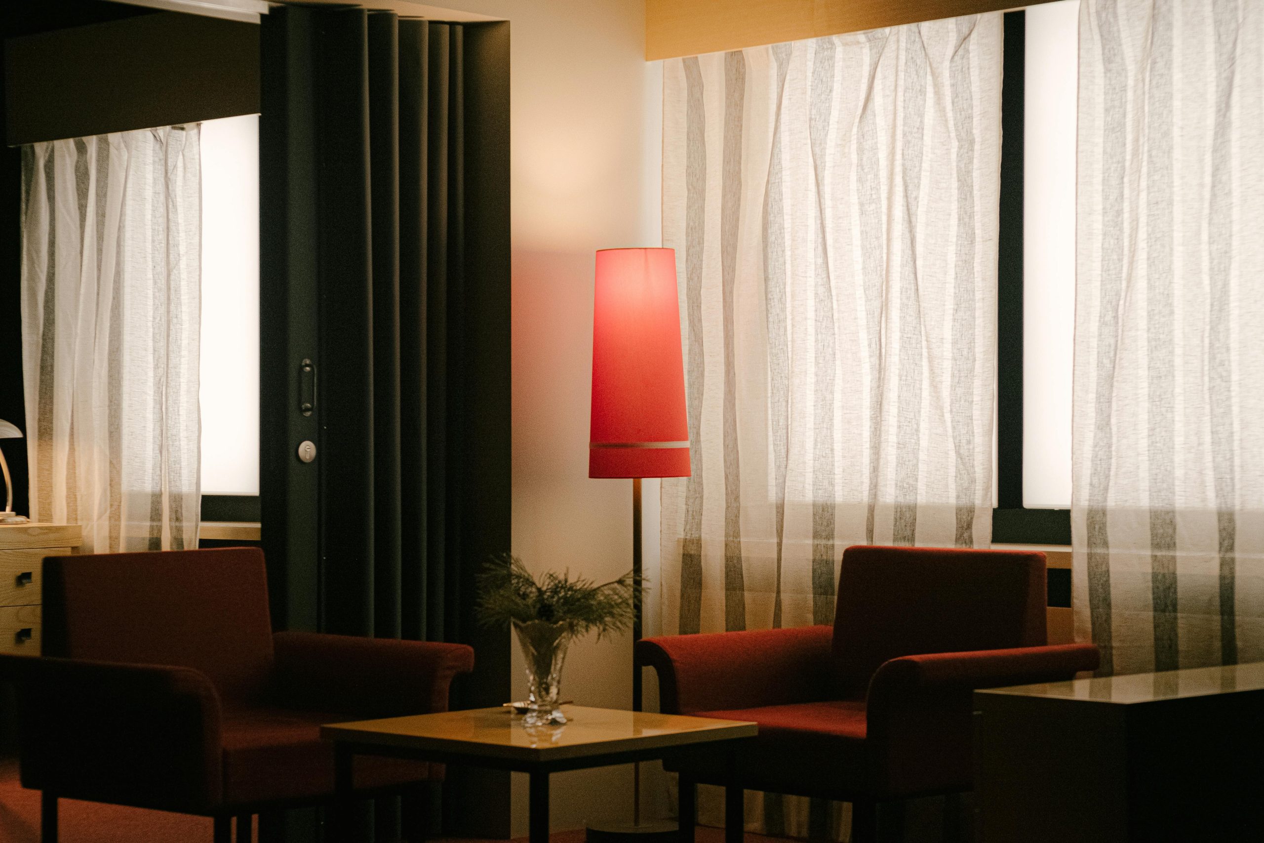 Stylish hotel room interior with art deco design featuring red chairs and ambient lighting.