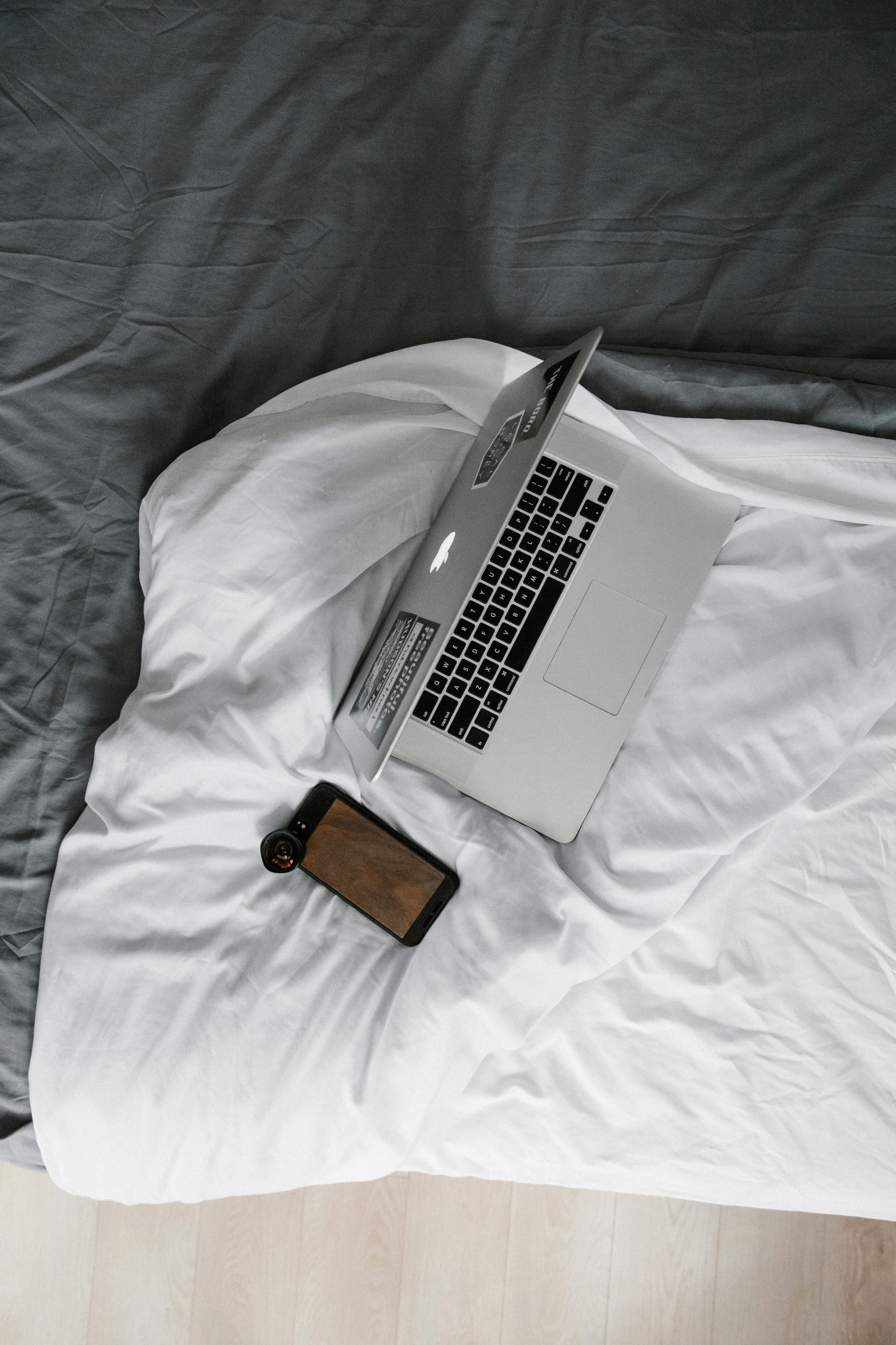 Minimalist overhead view of a laptop and smartphone on a cozy bed, ideal for remote work settings.