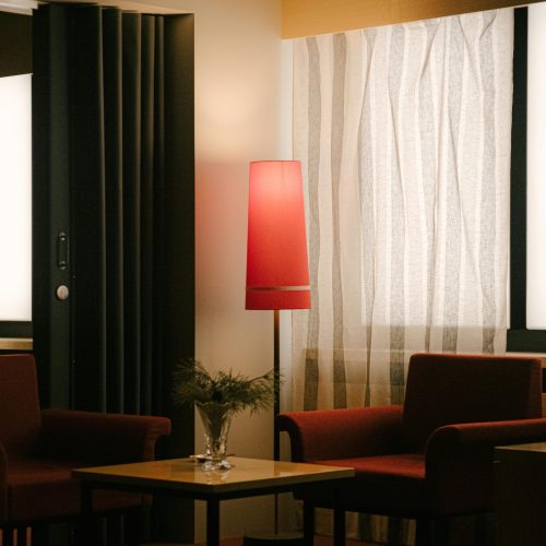 pexels-photo-15974645-15974645 Stylish hotel room interior with art deco design featuring red chairs and ambient lighting.